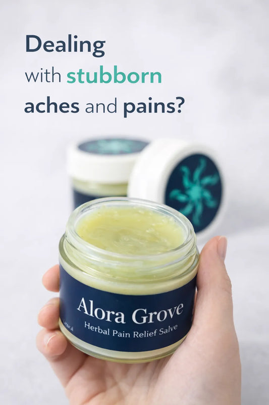 Two Alora Grove™ pain relief salve jars on a log with a natural forest background