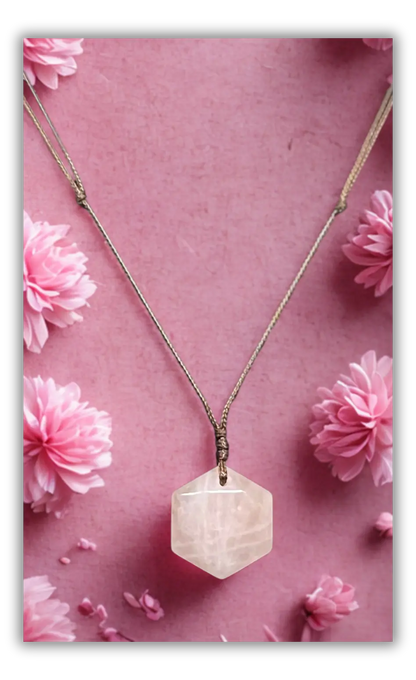 A hexagonal faceted pale pink gemstone pendant necklace on a delicate silver-toned chain, displayed against a pink background decorated with pink flowers.