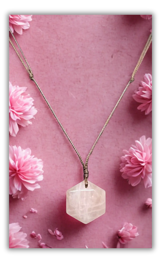 A hexagonal faceted pale pink gemstone pendant necklace on a delicate silver-toned chain, displayed against a pink background decorated with pink flowers.